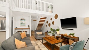 Una sala de estar moderna con un sofá gris, una mesa de centro de madera y un televisor montado en la pared.