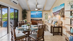 A spacious dining area with a round table, chairs, and ceiling fans. - Wailea Ekolu 104 2 Bedroom Condo (Kihei)