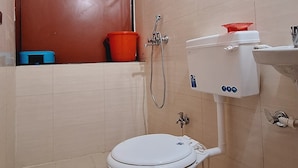 Une salle de bain avec des toilettes blanches, une douche et un lavabo.
