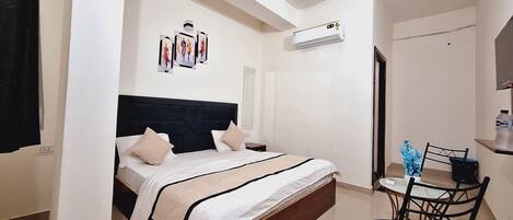A bedroom with a bed, bedside table, chair, and a small table with a vase.
