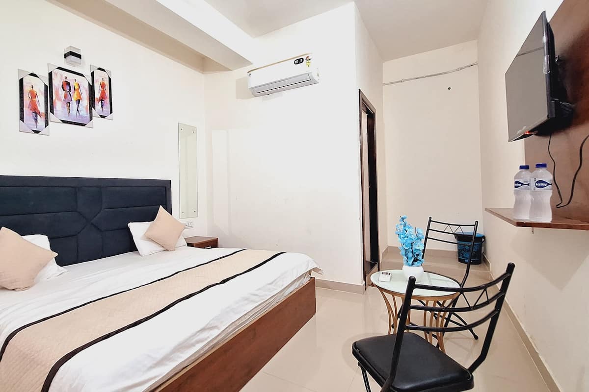 Une chambre d’hôtel équipée d’un lit, d’une chaise, d’une petite table, d’un téléviseur et d’un distributeur d’eau.