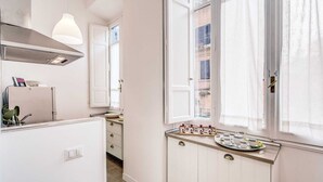 A bright kitchen with white cabinets, a window with sheer curtains, and a tray of tea cups on the counter.