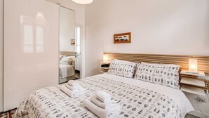 A bedroom with a large bed, bedside tables, a mirror, and a wall-mounted picture.
