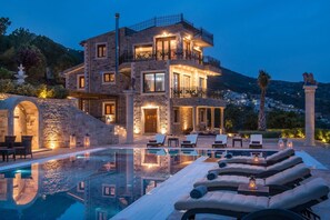 A multi-story stone building with a pool, lounge chairs, and a view of the surrounding landscape. - Lovely Sea Views   5 bedroom villa in Rodia (Rogdia)