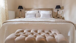 En pænt redt seng med en betrukken gavl, to sengeborde med lamper, og et skilt med teksten "SWEET HOME" på et af sengebordene.