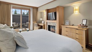 Ein Hotelzimmer mit einem großen Bett, einem Kamin, einem Fernseher und einem Schreibtisch mit Stuhl.