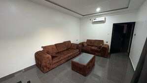 Ein Wohnzimmer mit zwei braunen Sofas, einem Couchtisch und einer weißen Klimaanlage an der Wand.
