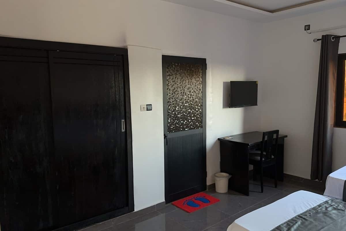 A bedroom with a bed, a desk, a chair, a TV, and a wardrobe.