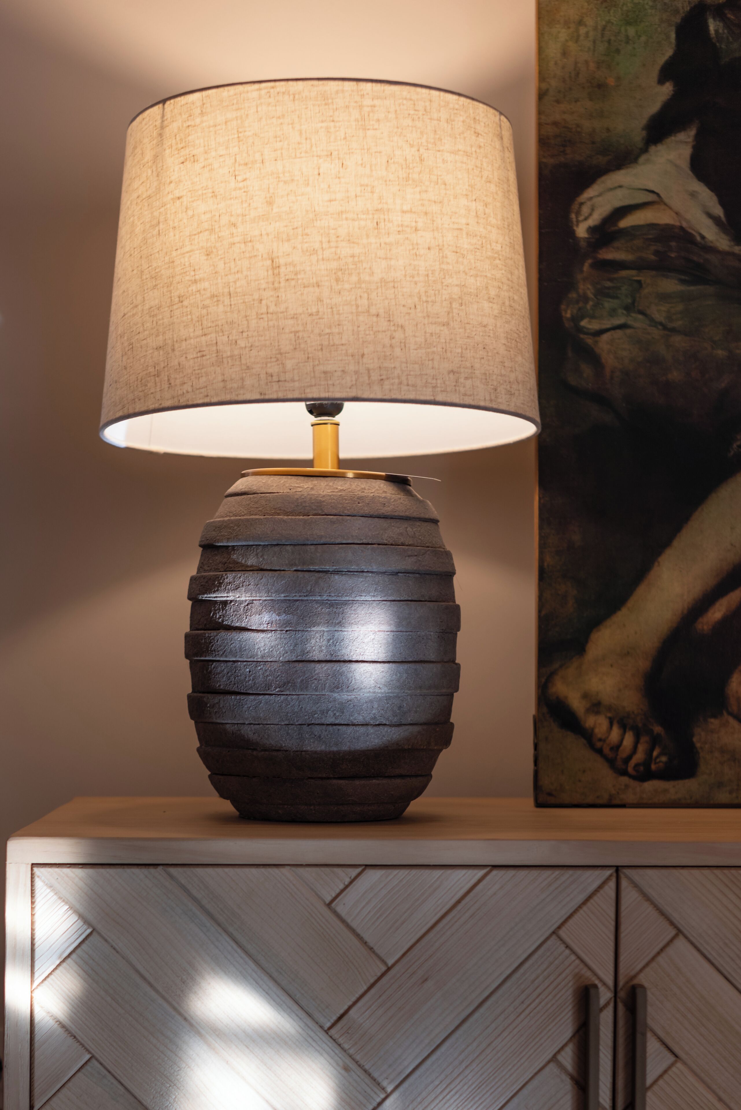 Een lamp met een structuurrijke kap op een houten kast.