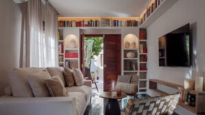 Un salon moderne avec un canapé, un fauteuil en osier, une table basse et des étagères remplies de livres.