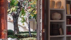 Un coin lecture confortable avec une bibliothèque, un fauteuil moelleux et une vue sur un arbre à l’extérieur.