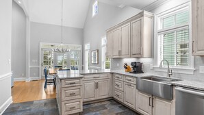 A spacious kitchen with light wood cabinets, a large sink, and a dining area with a table and chairs.