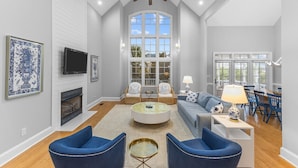 A spacious living room with a fireplace, two sofas, a coffee table, and a TV.
