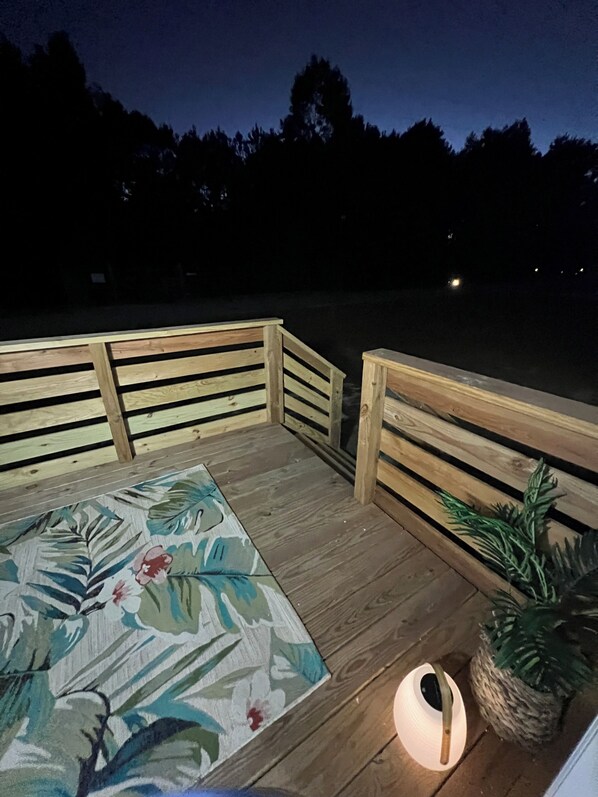 A wooden deck with a floral rug, a bench, and a potted plant. - Absolutely Darling private little oasis ! (Holly Ridge)