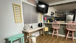 A compact living space with a kitchenette, a dining area with two chairs, a small table, and a bench. - Absolutely Darling private little oasis !  (Holly Ridge)