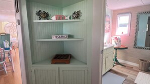 A room with a light green built-in shelving unit labeled "Bench House" containing decorative items and a chessboard. - Absolutely Darling private little oasis !  (Holly Ridge)
