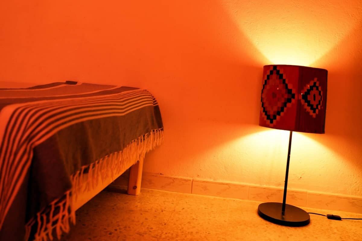 A room with a bed, a lamp, and two framed pictures on the wall.