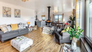 A spacious living room with a fireplace, a dining area, and a kitchen. - Towford Farm Bungalow (Jedburgh)