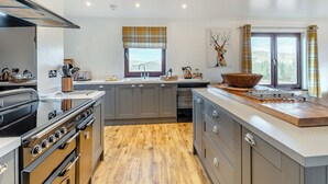 A modern kitchen with grey cabinets, a large island, and a view of the outdoors through a window. - Towford Farm Bungalow (Jedburgh)