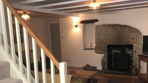 A living room with a fireplace, a sofa, and a staircase. - Quiet and secluded farmhouse, with far reaching views, spacious and comfortable  (Liskeard)