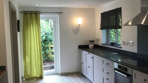 A modern kitchen with white cabinets, a black countertop, and patterned floor tiles. - Quiet and secluded farmhouse, with far reaching views, spacious and comfortable  (Liskeard)