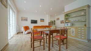 Ein Essbereich mit Holztisch und -stühlen, einer Couch, einem Schrank mit Geschirr und Kunstwerken an den Wänden.