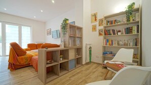 Ein Wohnzimmer mit einer Couch, einem Holzregal und einem weißen Sessel.