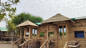 A rustic wooden cabin with a porch, a ladder, and a small window. - Sinbad Beach Resort (Saint Martin's Island)