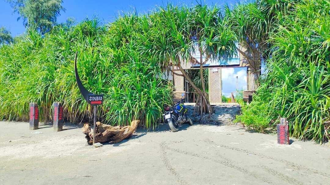 Un cartello con la scritta "SINBAD" davanti a un edificio immerso nel verde.
