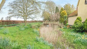 A garden with a pond, a wooden bridge, and a building with a tiled roof. - 2 bedroom accommodation in Fressingfield, near Eye (Fressingfield, near Eye)