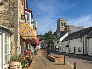 A narrow street lined with traditional buildings, a church with a clock tower, and a cyclist.