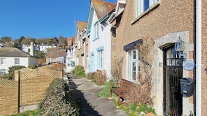 A narrow street lined with traditional houses, a wooden gate, and a bench.