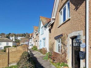 A narrow street lined with traditional houses, a wooden gate, and a bench.
