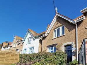 A row of terraced houses with distinct architectural styles, including a cottage with a black front door and a blue window.
