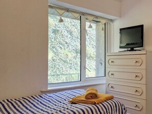 Une chambre à coucher avec un lit, une fenêtre, une commode et un téléviseur.
