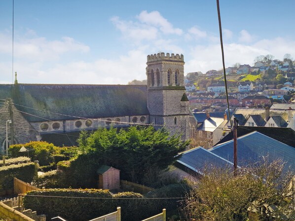 A historic building with a tower, surrounded by residential houses and greenery.