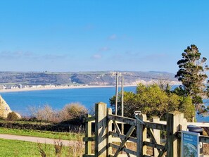 A coastal view with a wooden gate, a clear sky, and a distant shoreline.
