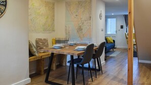 Un coin repas avec une table en bois, des chaises et une carte accrochée au mur.