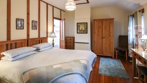 Una camera da letto con un letto grande, un armadio in legno, una scrivania e un lampadario.