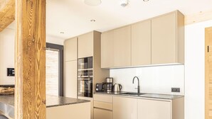 Une cuisine moderne dotée d’appareils électroménagers intégrés, d’un évier en acier inoxydable et de meubles de rangement de couleur claire.