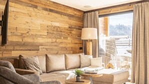Un salon moderne avec un mur en bois, un canapé, une table basse et une vue sur un paysage enneigé.