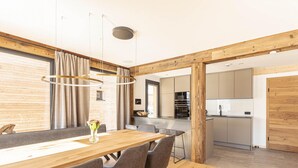 Une cuisine moderne dotée d’appareils électroménagers intégrés et un coin repas en bois avec une grande table et des chaises.