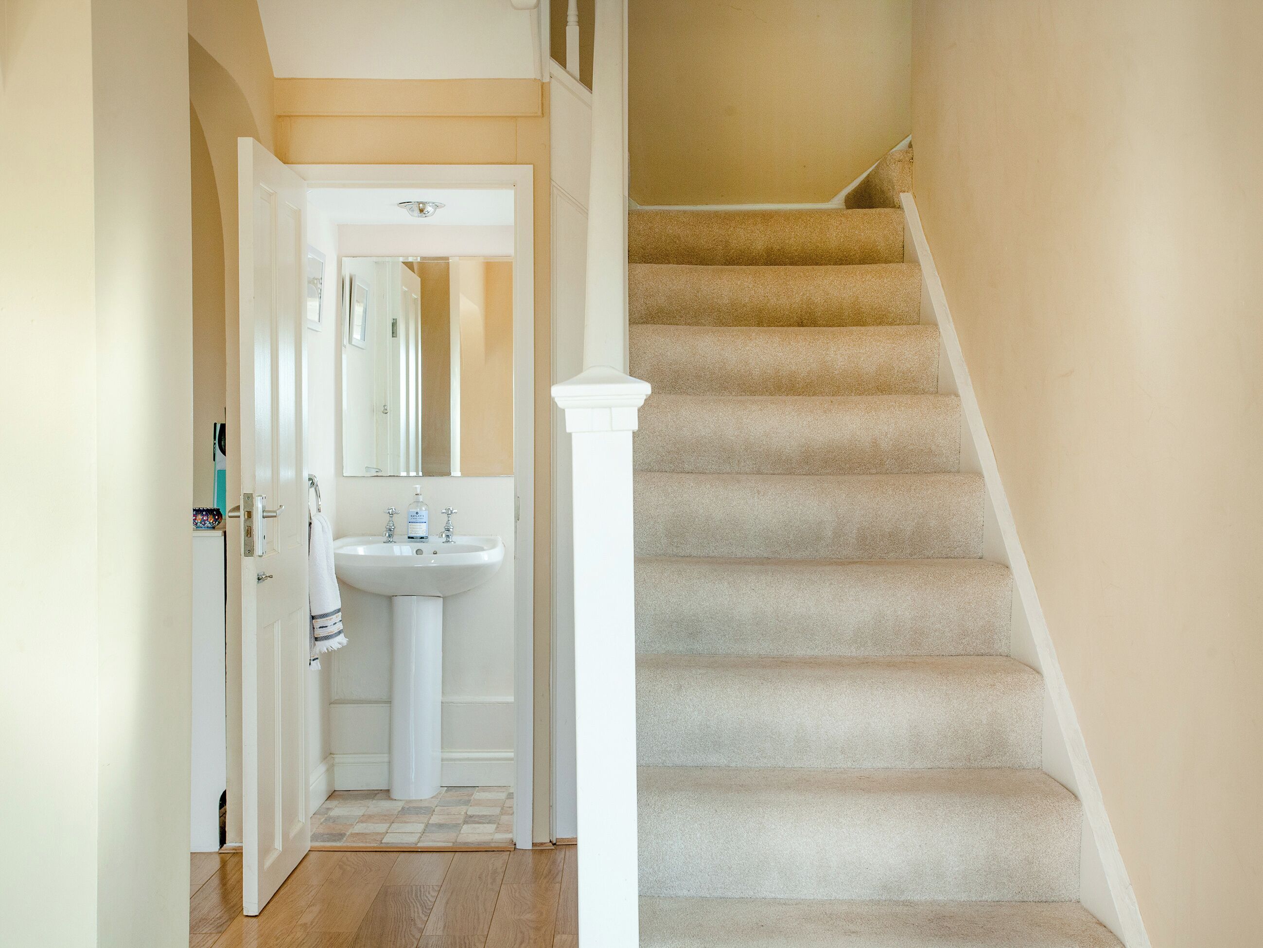 A staircase with beige carpeted steps and white railings, leading to an upper floor.