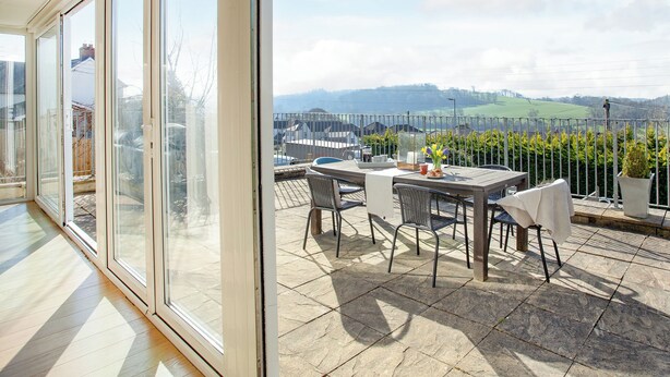A balcony with a table and chairs, a view of the countryside, and a clear sky. - 3 bedroom accommodation in Bishops Tawton, near Barnstaple (Bishops Tawton, near Barnstaple)