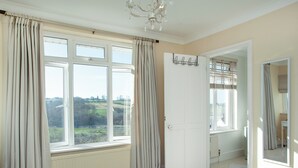 A bedroom with large windows, a bed with rolled towels, a chandelier, and a mirror. - 3 bedroom accommodation in Bishops Tawton, near Barnstaple (Bishops Tawton, near Barnstaple)