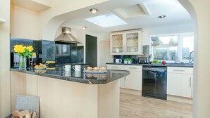 A modern kitchen with a central island, built-in appliances, and a view through an archway to another room. - 3 bedroom accommodation in Bishops Tawton, near Barnstaple (Bishops Tawton, near Barnstaple)