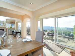 Un comedor con una mesa lista para dos personas, un sofá y vistas al exterior.