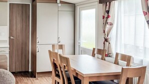 Kompakti keittiö, jossa on puiset kaapit ja ruokapöytä tuoleineen.