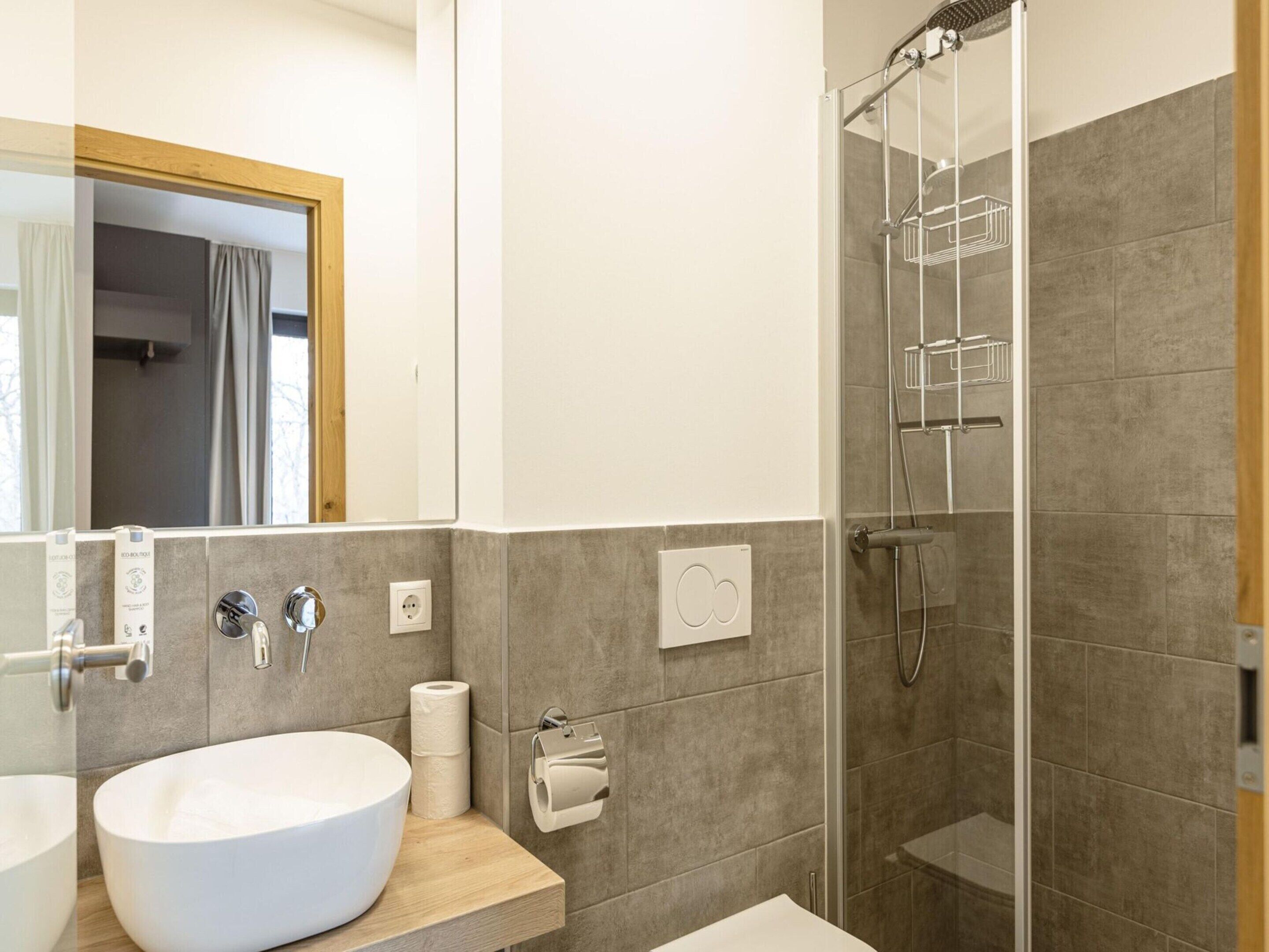 A modern bathroom with a large sink, a mirror, a shower with a glass door, and a towel rack.