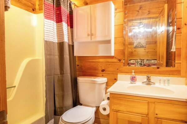 Un baño de cabaña de madera con bañera, inodoro y armarios de madera.
